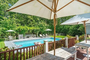 Ein Garten mit Schwimmbad, Holzterrasse und Gartenmöbeln.