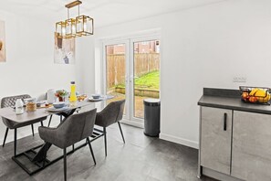 A modern kitchen with a dining area, a large window, and a view of the backyard. - Family-Friendly 3BR Home with Games (Blackburn with Darwen)