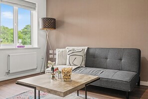 Un salon avec un canapé, une table basse, une lampe et une fenêtre donnant sur un beau paysage.