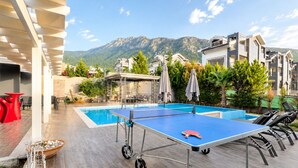 A pool table, a pool, and a mountain view.