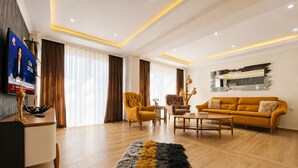 A modern living room with a sofa, armchairs, a coffee table, and a TV.