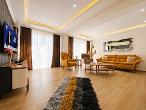 A modern living room with a sofa, armchairs, a coffee table, and a TV. - The Villa Premium Rose in Oludeniz (Muğla)