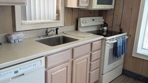 Una cocina con armarios de madera, microondas, estufa y lavavajillas.