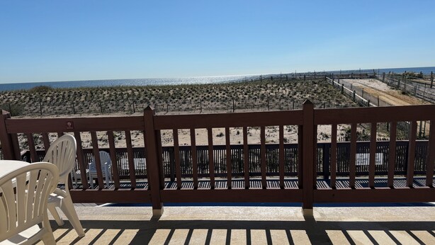 Una terraza de madera con vista a la playa y al océano.