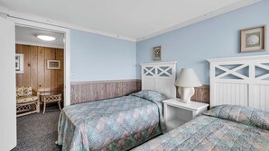 Un dormitorio con dos camas, una mesita de noche, una lámpara y una silla.