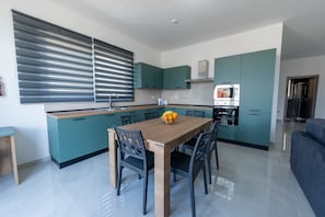 Eine moderne Küche mit Türkis-Schränken, einem Holzespeisetisch und einer Obstschale.