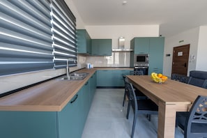 Eine moderne Küche mit türkisfarbenen Schränken, einer Holz Arbeitsplatte, einer Edelstahl-Spüle und einer Mikrowelle.