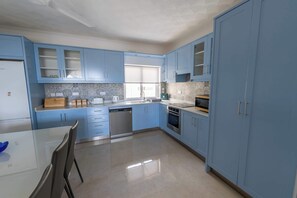 A modern kitchen with blue cabinets, a dishwasher, an oven, and a window. - Ghajnsielem 3BDR Flat with Views - NO Lift (Għajnsielem)