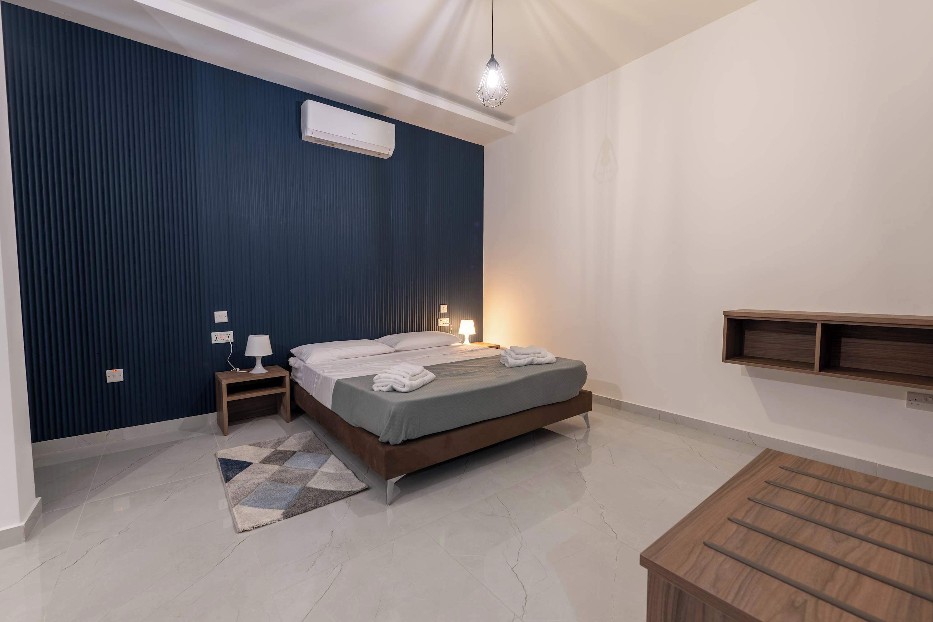 Ein modernes Schlafzimmer mit einem Bett, Nachttischen, einer Lampe und einer Pendelleuchte.