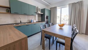 Uma cozinha moderna com armários verde-água, uma mesa de jantar de madeira e um forno embutido.