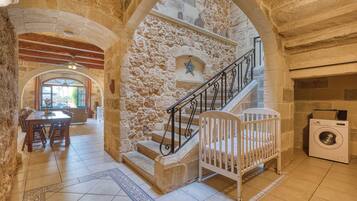 Interior con paredes de piedra, una escalera, zona de comedor y lavadora.