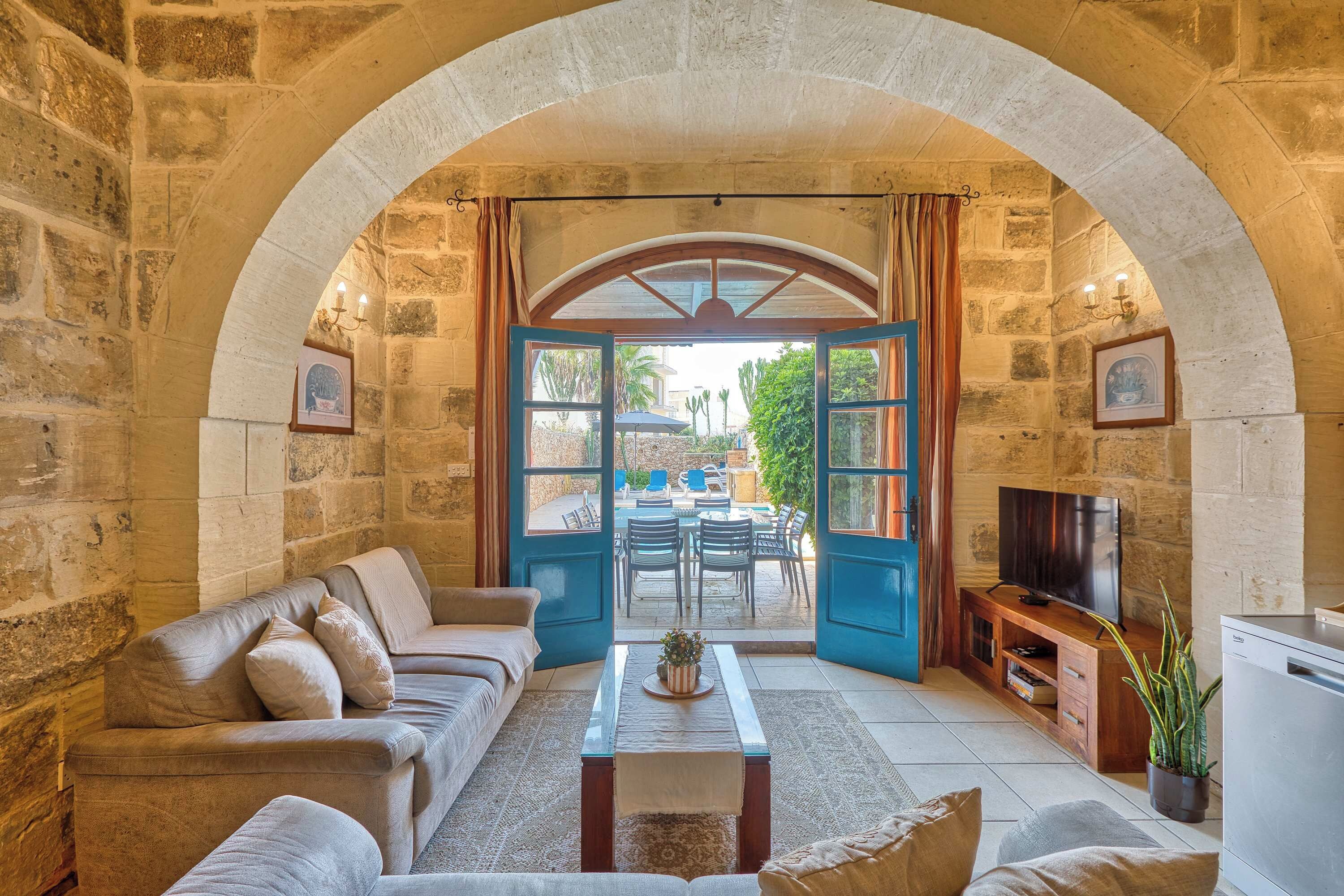 Una sala de estar acogedora con pared de piedra, un sofá, una mesa de centro y un televisor.