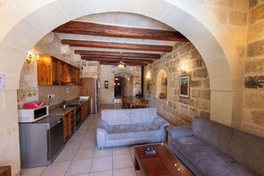 A kitchen with a microwave, cabinets, and a dining area with a sofa and table.