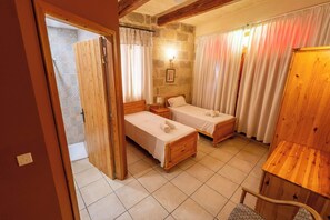 Une chambre à coucher avec deux lits en bois, une table de chevet en bois, une chaise et une armoire en bois.