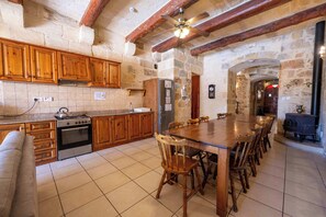 Une cuisine avec des meubles de rangement en bois, une cuisinière, un réfrigérateur et une table à manger avec des chaises.