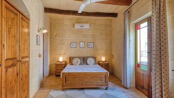 Un dormitorio con una cama de madera, un ventilador de techo y una pared de piedra.