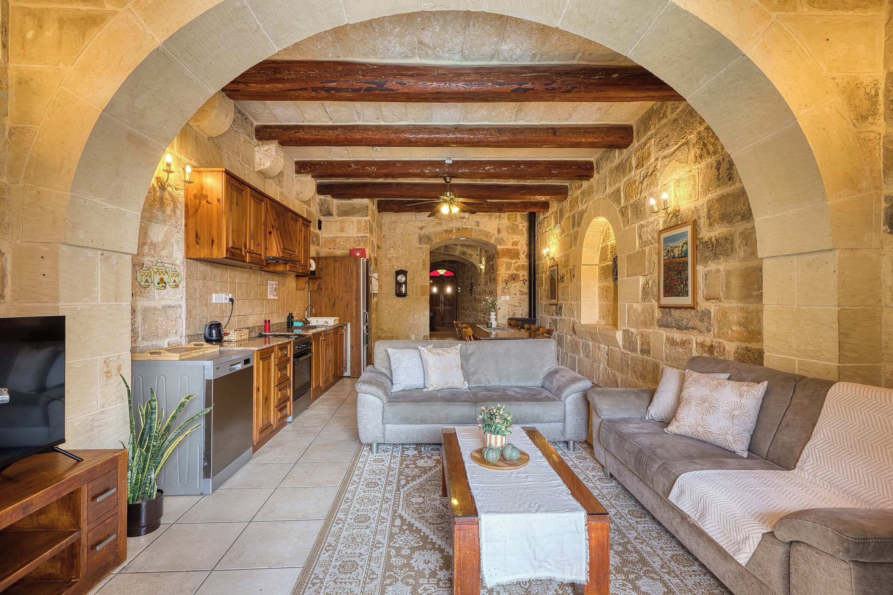 A cozy interior with a stone archway, a kitchen, a living area with a sofa, and a dining table.