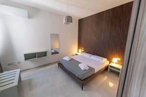 Ein modernes Hotelzimmer mit einem großen Bett, Nachttischen, einer Wandhalterung und einer Decken-Klimaanlage.