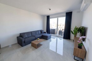 Ein modernes Wohnzimmer mit einer Eckcouch, einem Holztisch und einem Blumentopf.