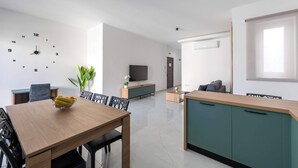Ein modernes Wohnzimmer mit Essbereich, einem Fernseher und einer Uhr an der Wand.