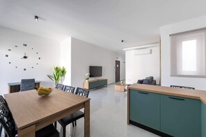Ein modernes Wohnzimmer mit Essbereich, einem Fernseher und einer Uhr an der Wand.