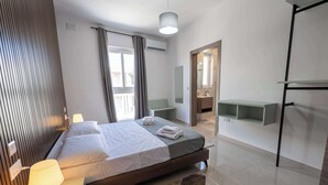 A modern hotel room with a bed, bedside lamp, and a view of the bathroom. - Swieqi Brand New 3BDR Flat- Spacious Getaway - FL7 (Is-Swieqi)