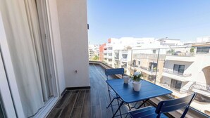 A balcony with a table and chairs, a potted plant, and a view of buildings. - Swieqi Brand New 3BDR Flat- Spacious Getaway - FL7 (Is-Swieqi)