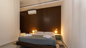 A modern bedroom with a bed, bedside lamps, and a wall-mounted air conditioner. - Stunning New 3BDR Apartment in Swieqi - FL9 (Is-Swieqi)