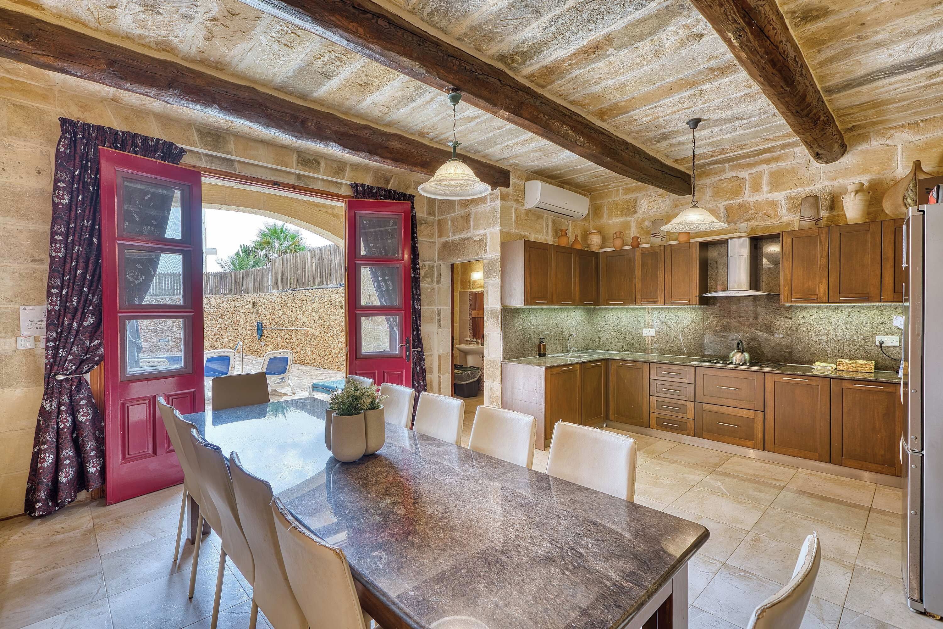 A rustic kitchen with wooden cabinets, a dining area with a table and chairs, and a red door with glass panels.