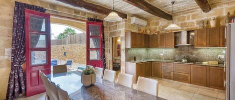 A rustic kitchen with wooden cabinets, a dining area with a table and chairs, and a red door with glass panels.