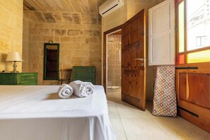 Ein Zimmer mit einem Bett, einem grünen Kommode, einem Holzschrank und einem Fenster mit gemusterten Vorhängen.