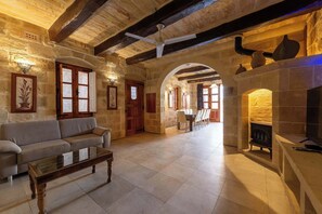 Una habitación con piso de piedra, una chimenea, un sofá y un comedor.