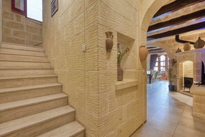 A stone staircase leading to a room with a fireplace and a dining area. - Tan Nanna 5 BDR Farmhouse by PMI Malta (Ix-Xagħra)
