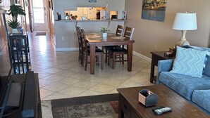 A living room with a dining table, sofa, coffee table, and a TV stand. -  2-bedroom condo in charming Cape Canaveral with amazing ocean views (Cape Canaveral)