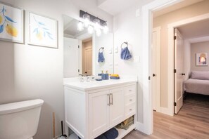 Een moderne badkamer met een witte wastafel, een grote spiegel en een toilet.