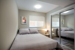 Une chambre à coucher avec un lit, des tables de chevet, une fenêtre et un miroir.