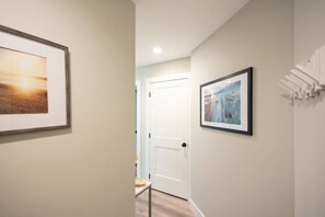 Un couloir avec deux tableaux encadrés accrochés aux murs, une porte blanche et un radiateur sur la droite.