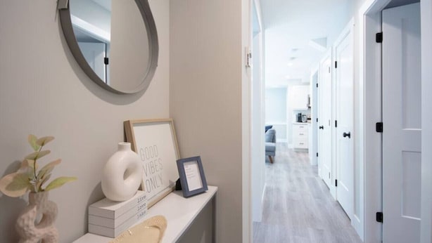 A hallway with a mirror, a framed sign, a vase, and a plant.