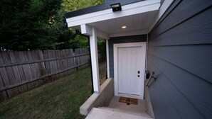 A house with a white door, a small porch, and a wooden fence in the background.