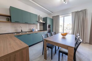 Eine moderne Küche mit Türkis-Schränken, einem Holzespeisetisch und einem Einbauofen.