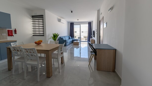 Un salon moderne comprenant un canapé, une table à manger avec des chaises, un piano et une grande fenêtre avec des rideaux.