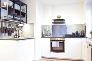 Eine moderne Küche mit weißen Schränken, einem Edelstahlkochfeld und einem eingebauten Backofen.