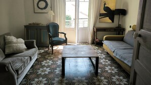 A living room with a sofa, armchair, a table, a lamp, a chessboard, and a painting. - Home 10 minutes from the beaches, between sea and mountains—downtown + garages (Perpignan)
