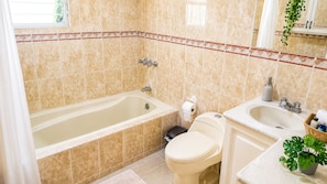 Ein Badezimmer mit Badewanne, Toilette, Waschbecken und einem Blumentopf.