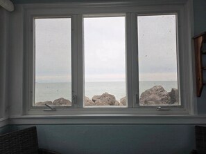 Ein Fenster mit Blick auf das Meer und die Felsen.