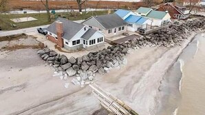 A coastal property with a house, a dock, and a rocky shoreline. - Oak Harbor Lake Erie Beach Front Cabin 3Bed 1Bath (Oak Harbor)