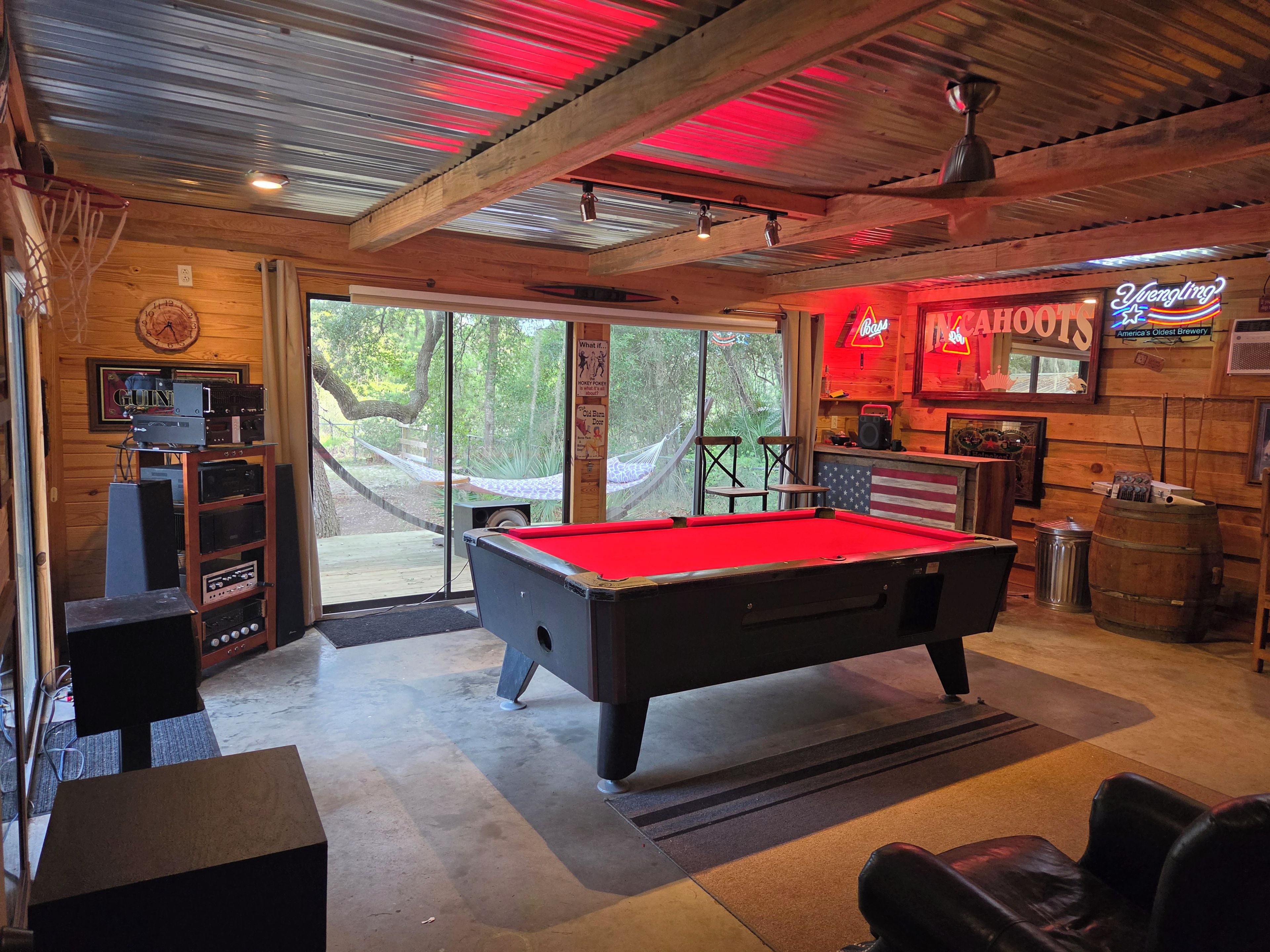 A pool table in a room with wooden walls and a large window.