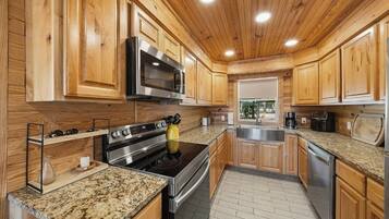 A kitchen with wooden cabinets, stainless steel appliances, granite countertops, and a window with a view.