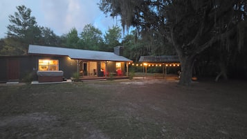 A rustic cabin with a porch, outdoor seating, and string lights.