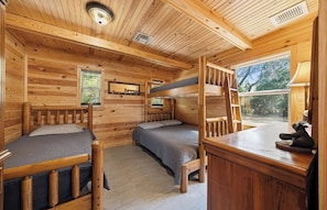 Une cabine équipée de deux lits superposés, d’un bureau et d’une fenêtre donnant sur un paysage verdoyant.